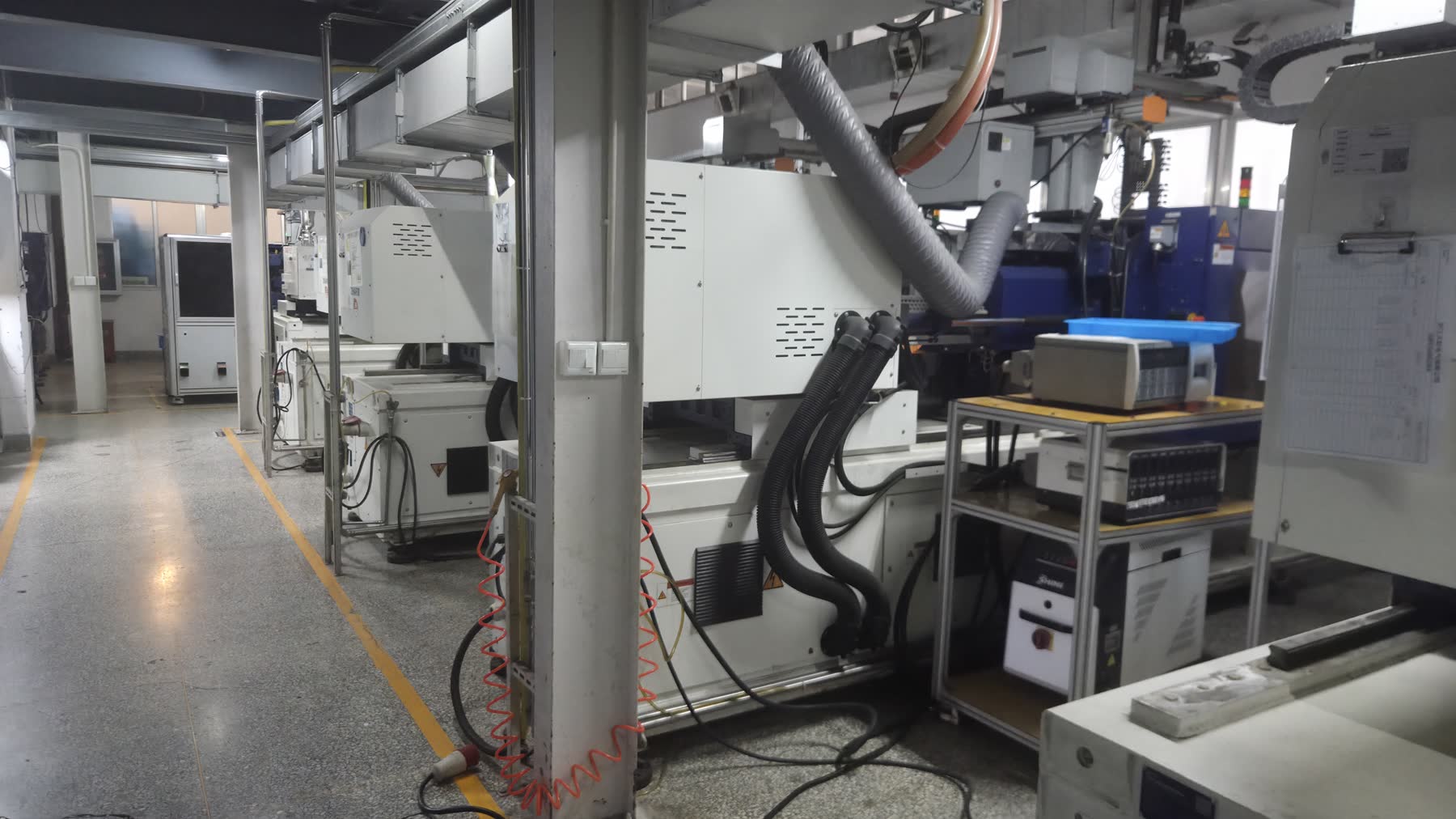 Real injection molding workshop equipment showing molding machine and auxiliary pipelines