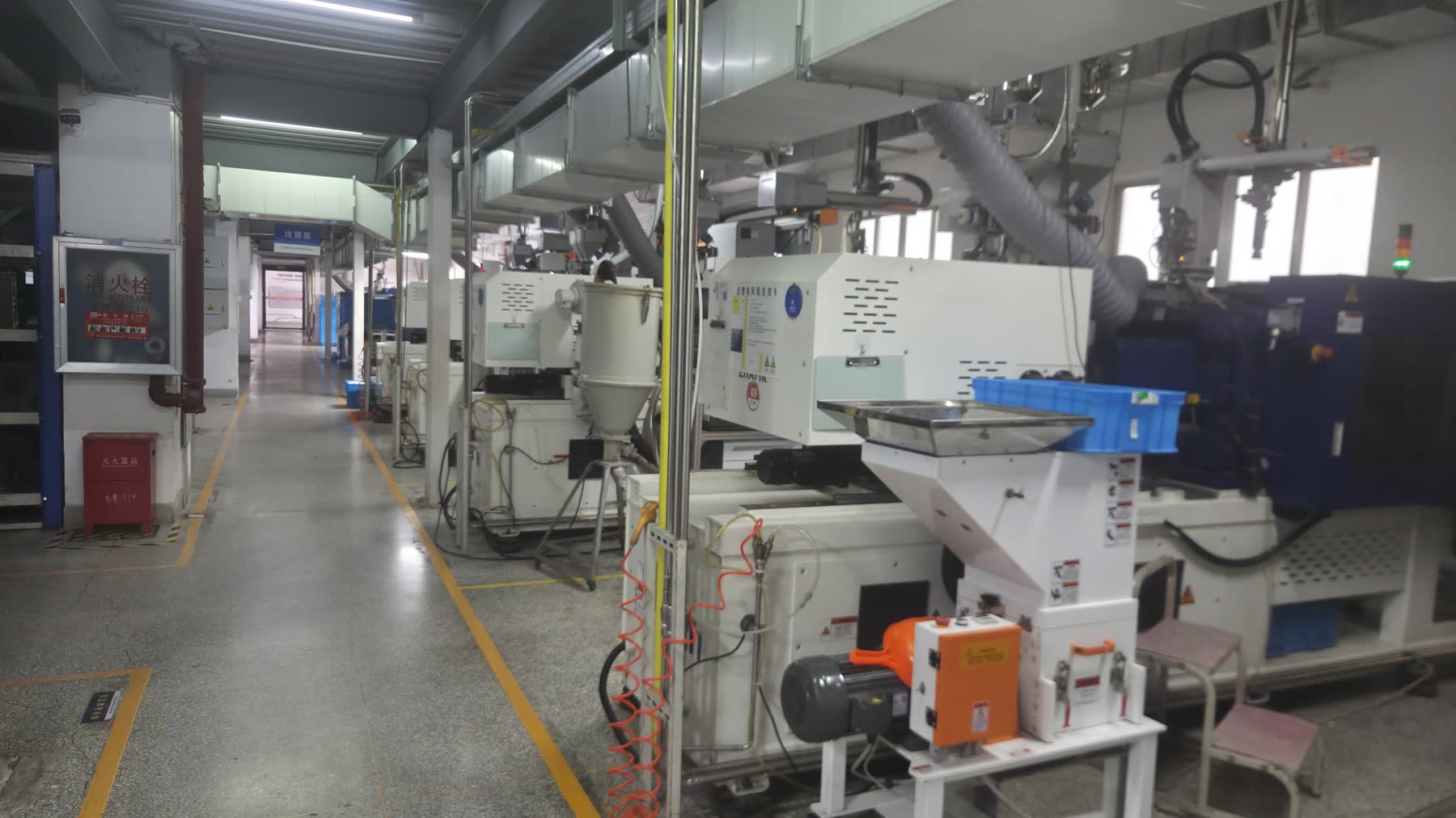 Real injection molding workshop equipment showing molding machine hopper and production aisle